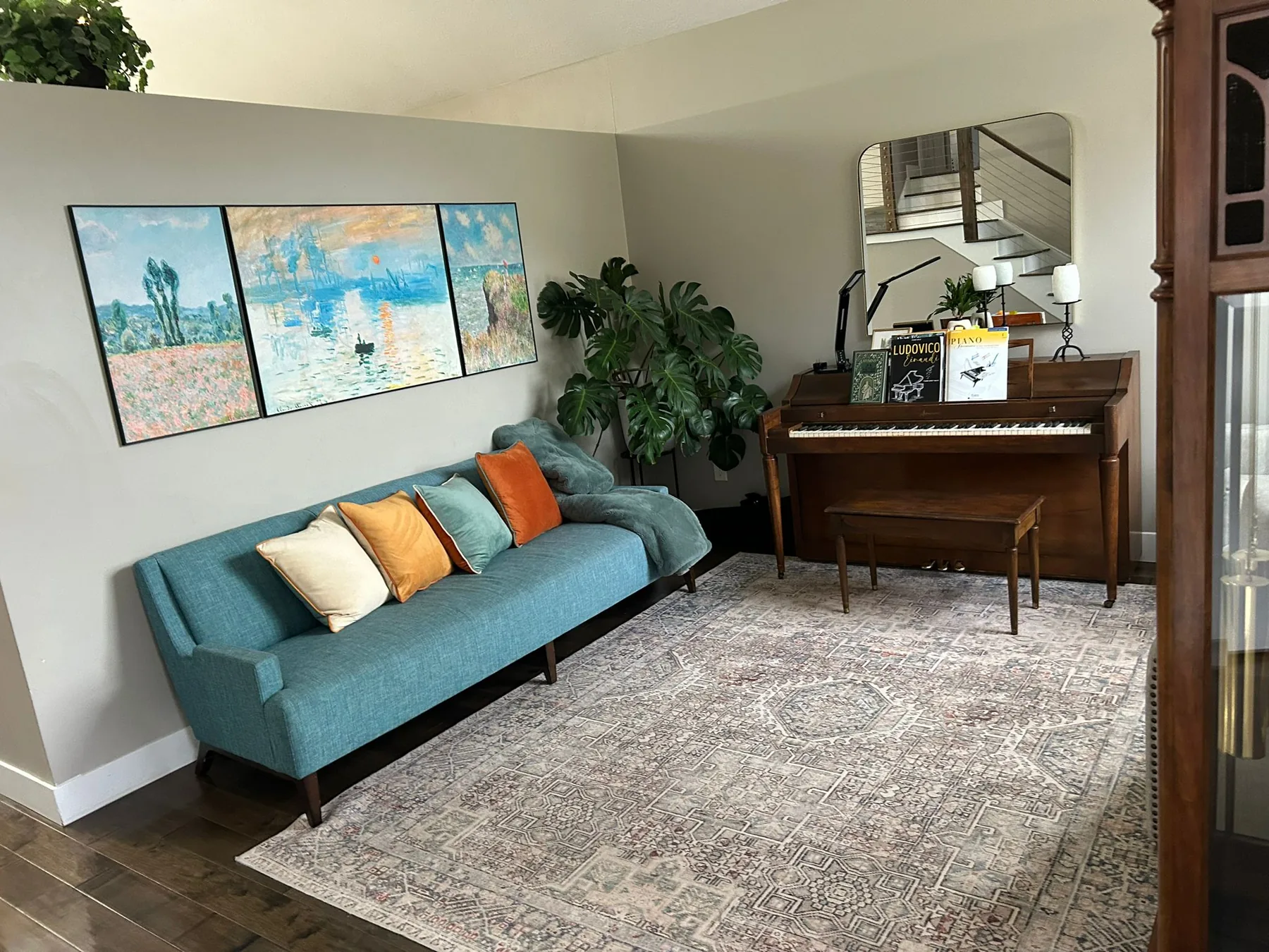 Tidy living room with a teal sofa, clean rug and dusted piano